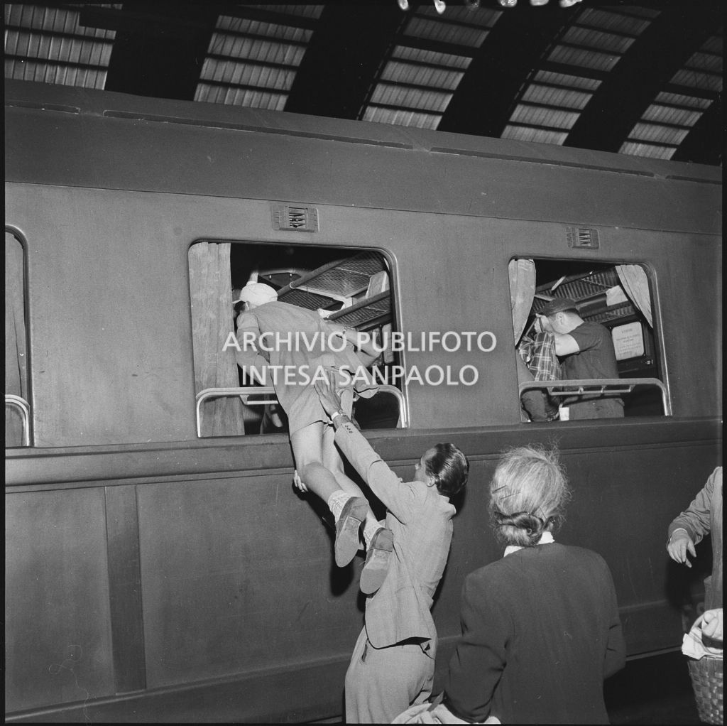 Un uomo aiuta un bambino ad entrate dal finestrino di un treno in partenza dalla stazione Centrale di Milano<br>222857