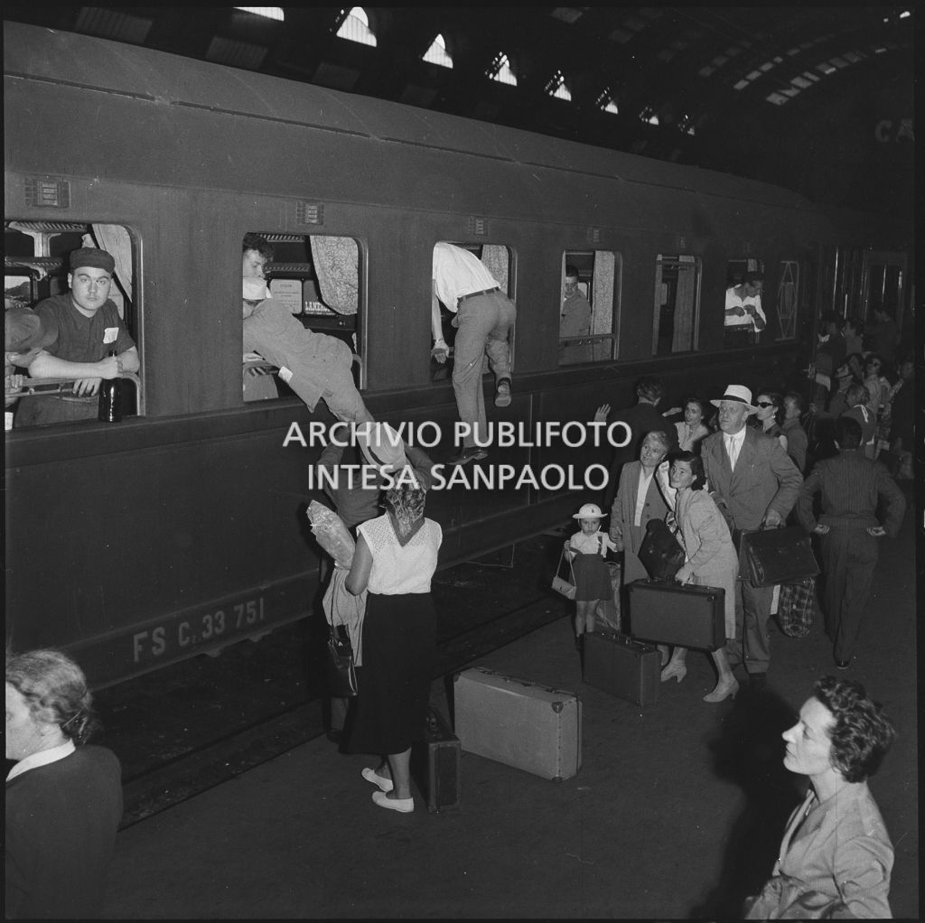 Uomini e bambini entrano dal finestrino di un treno in partenza dalla stazione Centrale di Milano<br>222860