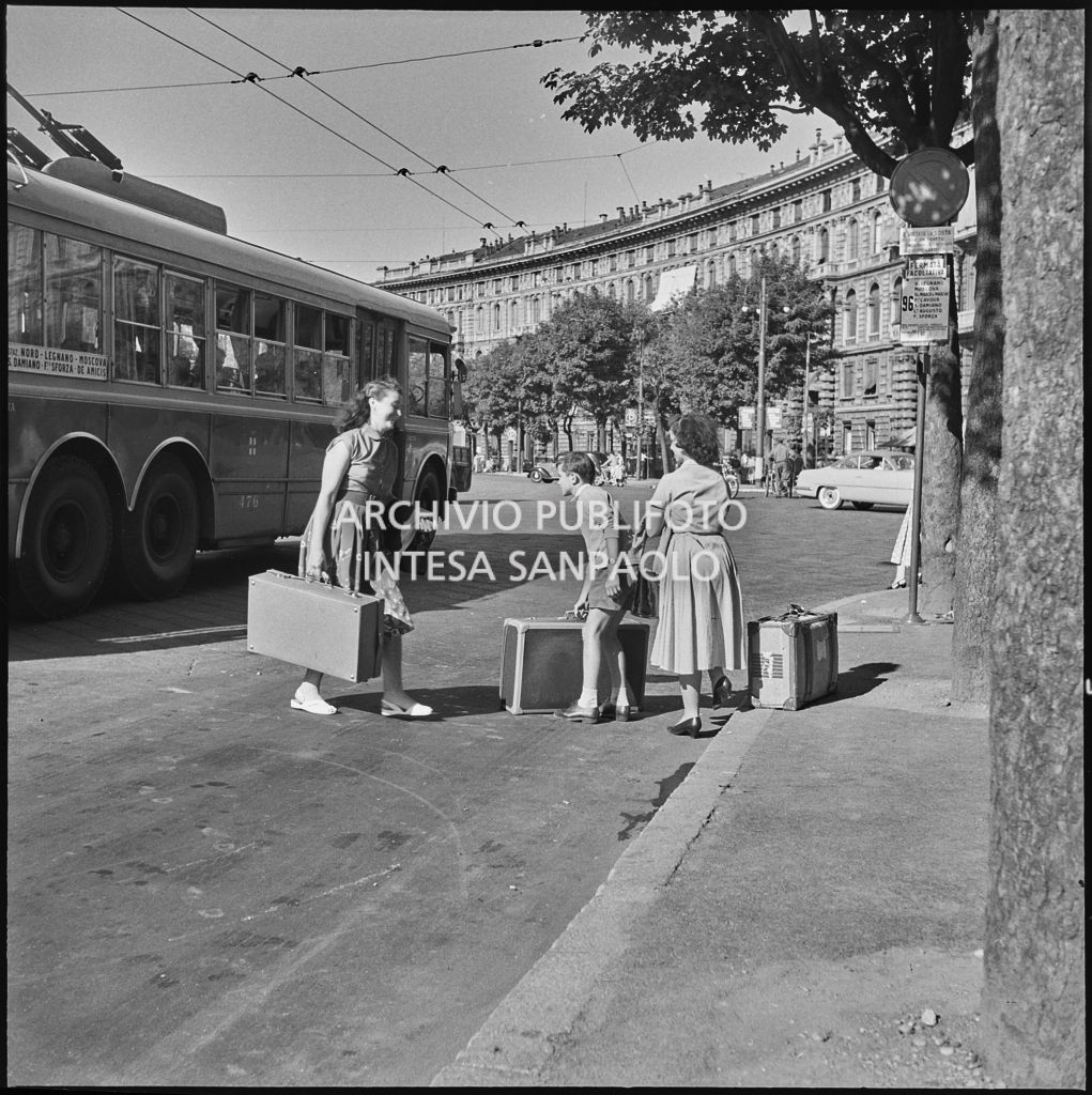 Due donne ed un bambino con delle valigie sul ciglio della strada a Milano<br>222864