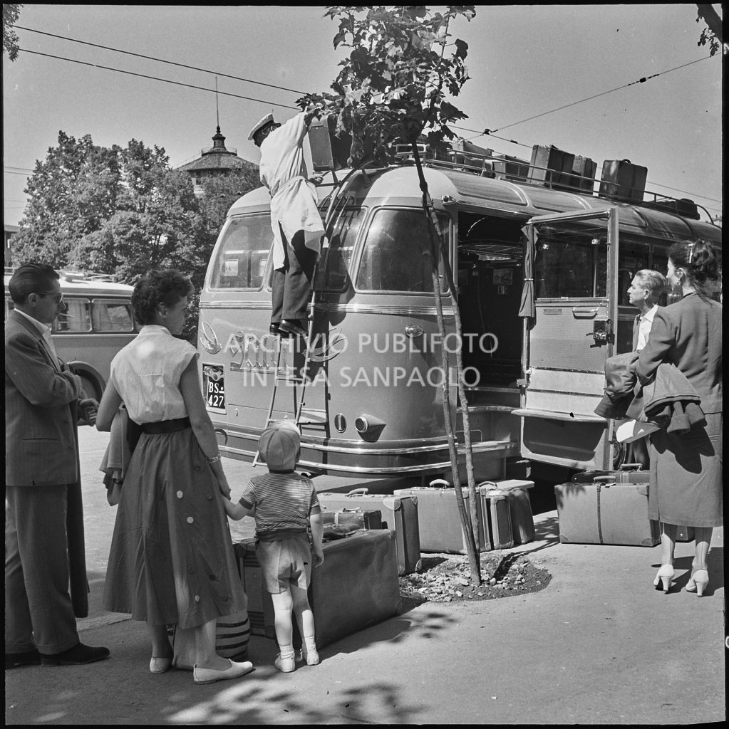 Gli autisti sistemano le valige dei passeggeri sul tetto di un pullman nei pressi del Castello Sforzesco di Milano<br>222865