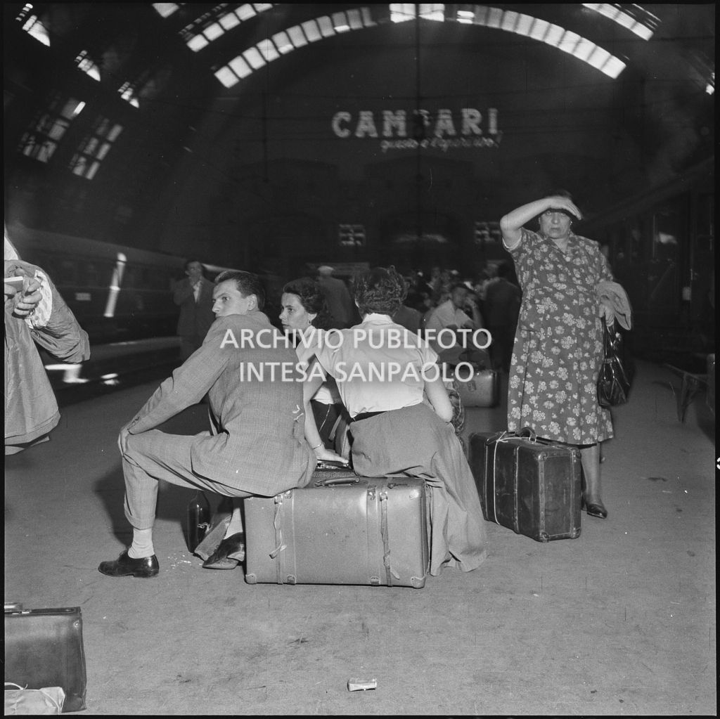 Alcune persone sedute sulle valige in attesa del treno per le vacanze estive alla stazione Centrale di Milano<br>222868