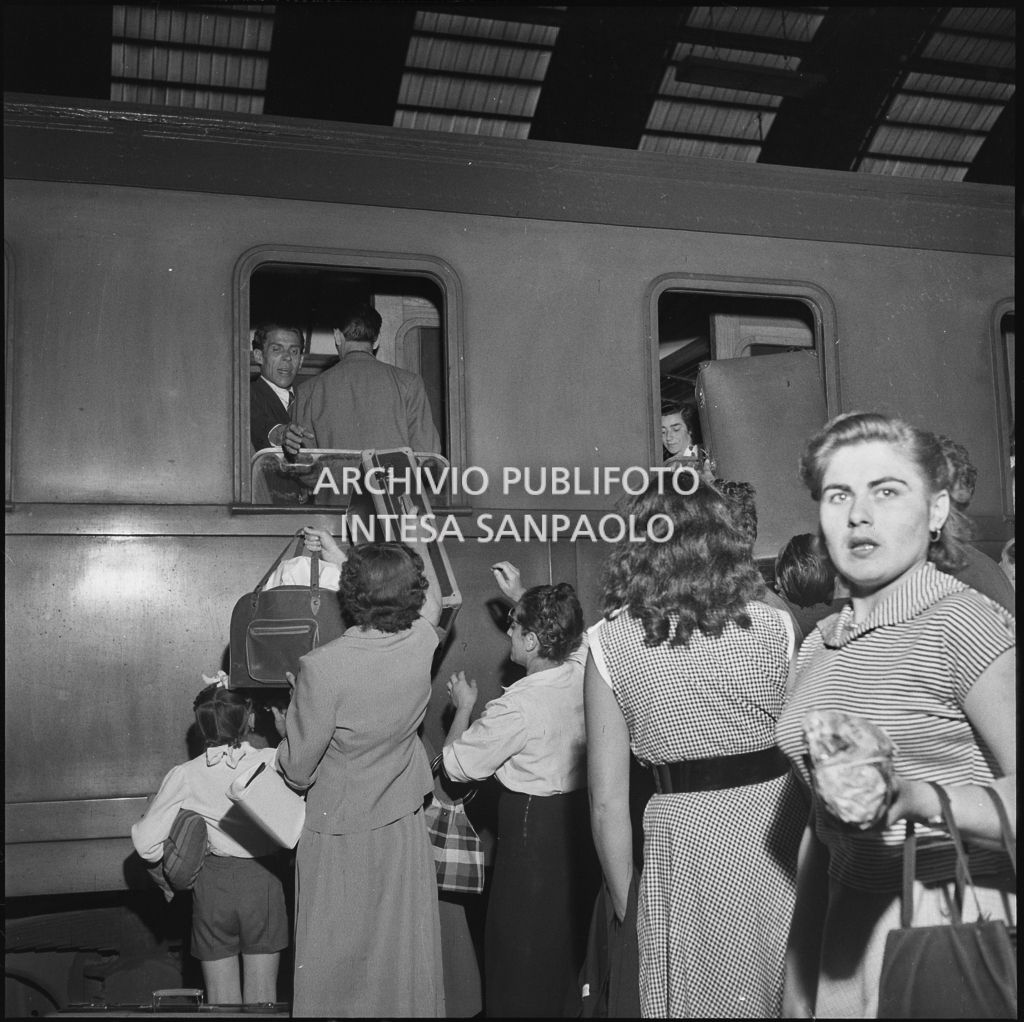 Una donna passa le valige ad un uomo attraverso il finestrino di un treno in partenza dalla stazione Centrale di Milano<br>222870