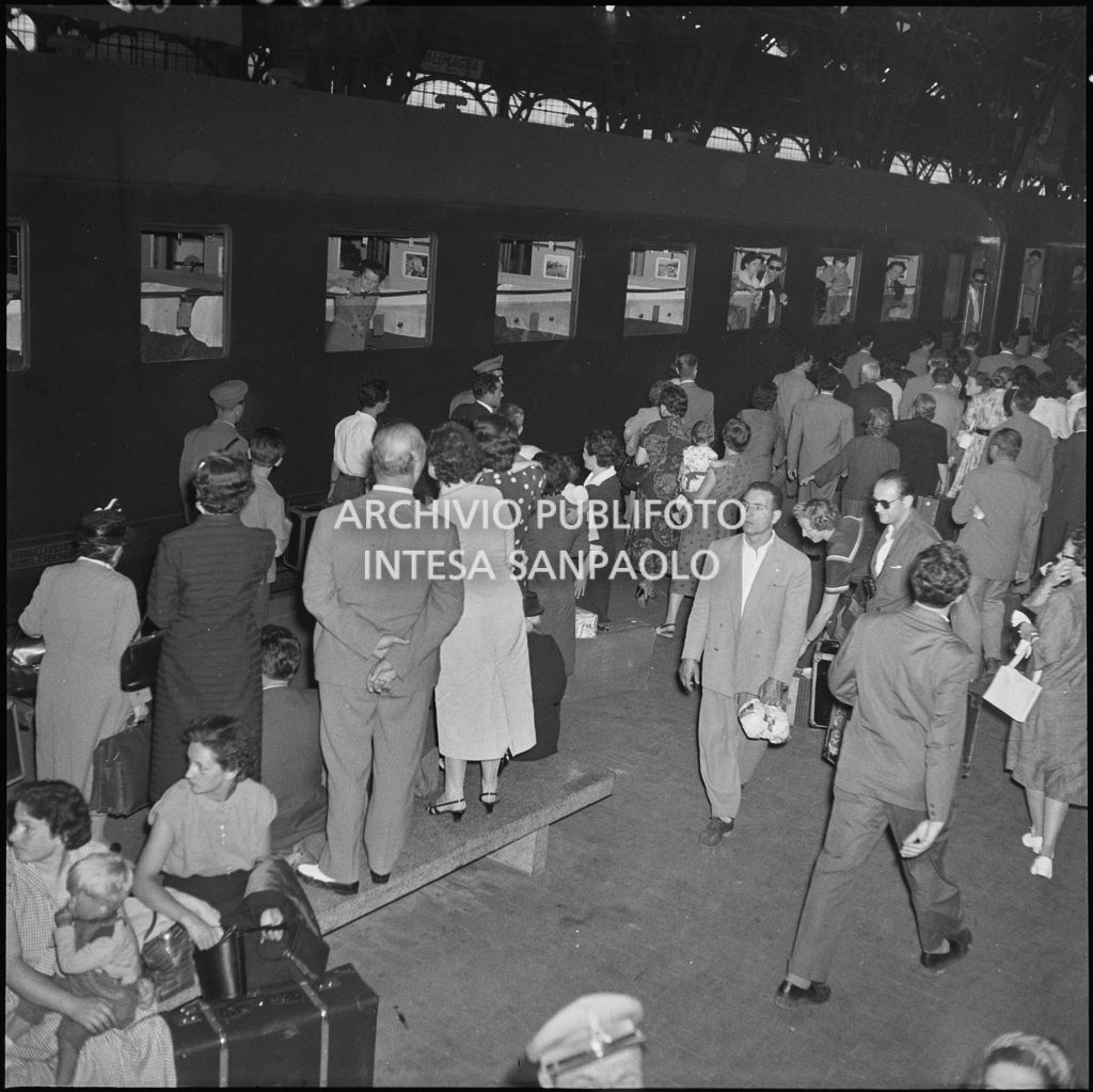 Treno in partenza e passeggeri con valige sulla banchina della stazione Centrale di Milano<br>222873