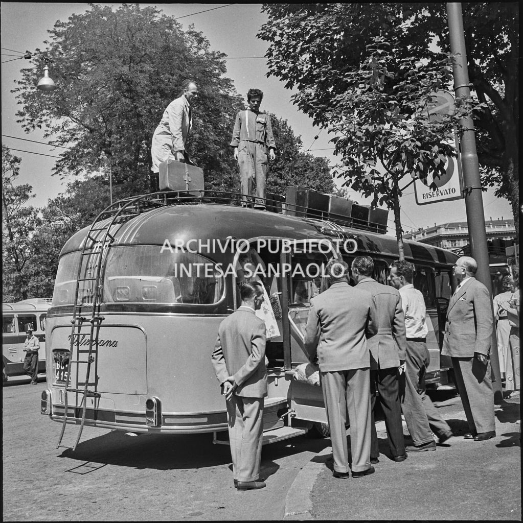 Gli autisti sistemano le valige dei passeggeri sul tetto di un pullman nei pressi del Castello Sforzesco di Milano<br>222888