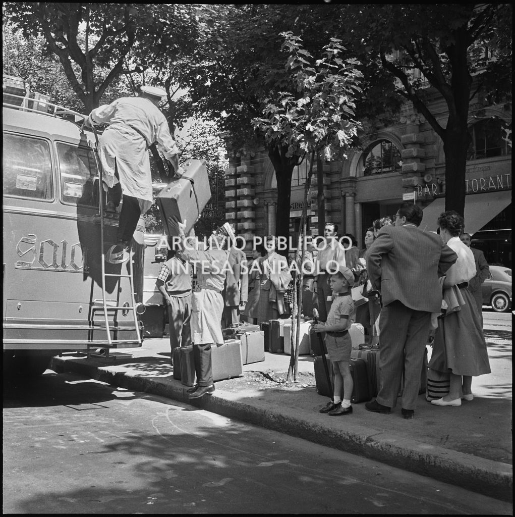 Gli autisti sistemano le valige dei passeggeri sul tetto di un pullman nei pressi del Castello Sforzesco di Milano<br>222889