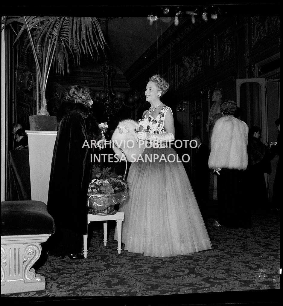 Una spettatrice con la fiorista della Scala in occasione della serata inaugurale della stagione lirica 1954-1955 del Teatro alla Scala con l'opera "La Vestale", di Gaspare Spontini, diretta da Antonino Votto, con la regia di Luchino Visconti