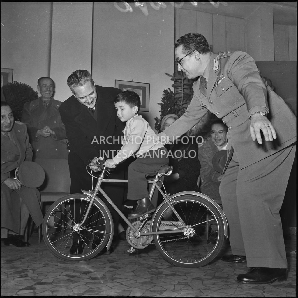 Il ministro delle Finanze Roberto Tremelloni (a sinistra) consegna un regalo al figlio di un finanziere nella caserma della Guardia di Finanza di via Melchiorre Gioia a Milano<br>240276