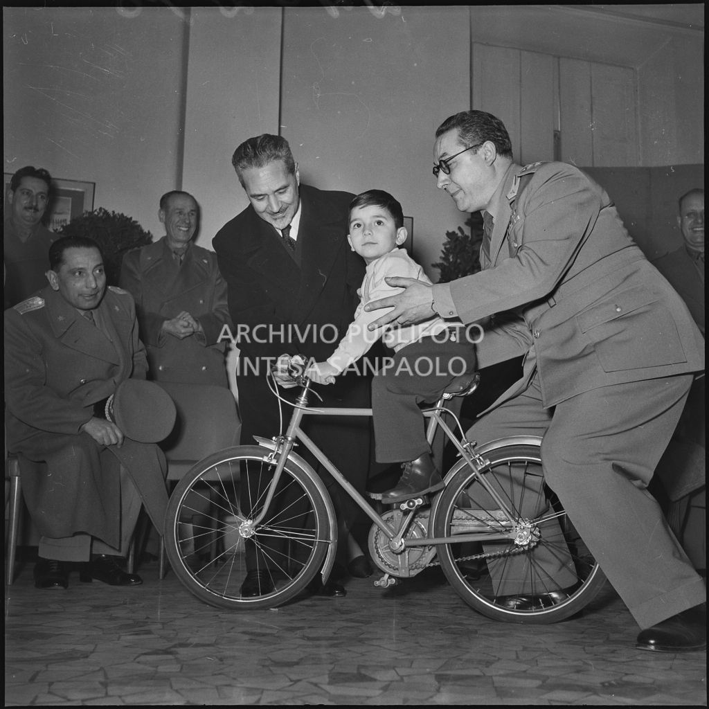 Il ministro delle Finanze Roberto Tremelloni (a sinistra) consegna un regalo al figlio di un finanziere nella caserma della Guardia di Finanza di via Melchiorre Gioia a Milano<br>240298