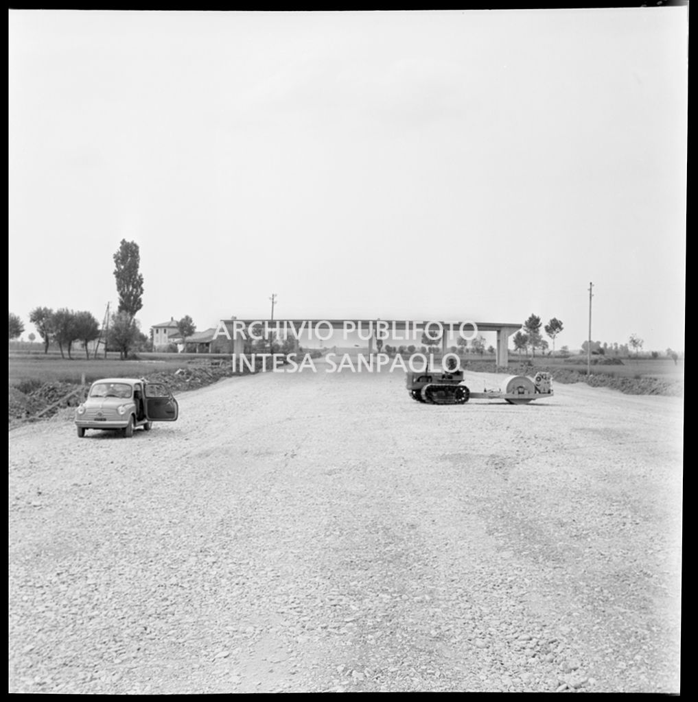 Una Fiat 600 e uno schiacciasassi nel cantiere per la costruzione dell'Autostrada del Sole nel tratto Piacenza-Pontenure<br>383257
