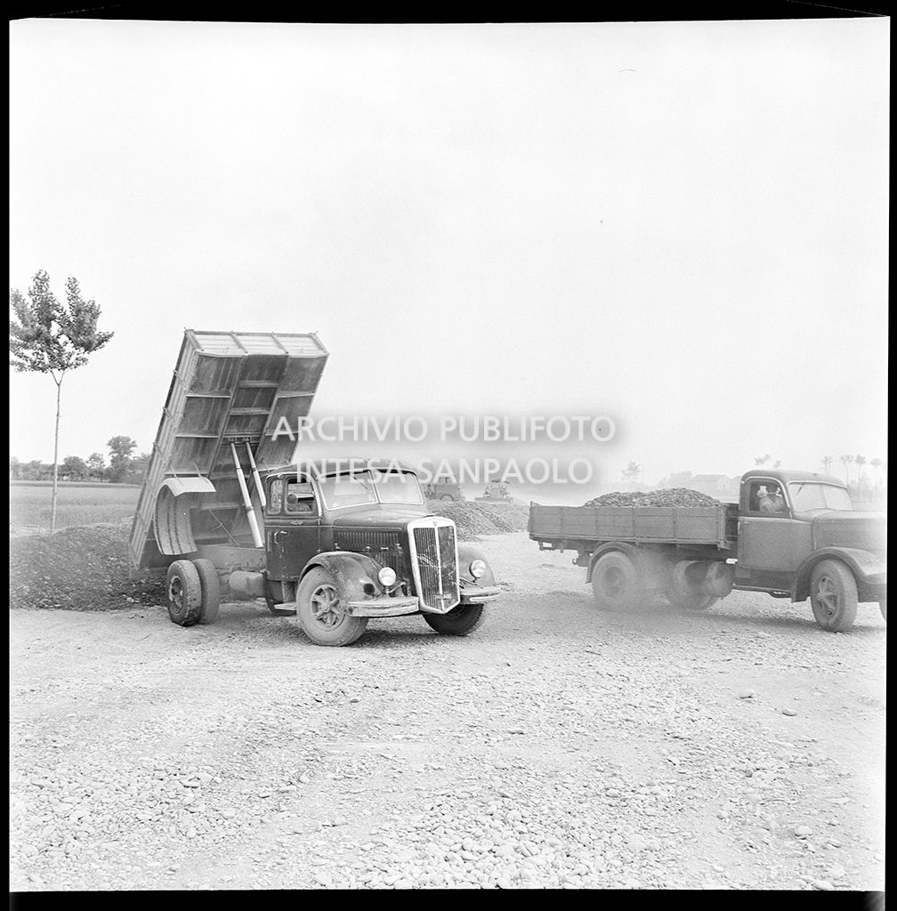 Scarico materiale nel cantiere per la costruzione dell'Autostrada del Sole nel tratto Piacenza-Pontenure visto dall'interno di una Fiat 600<br>383261