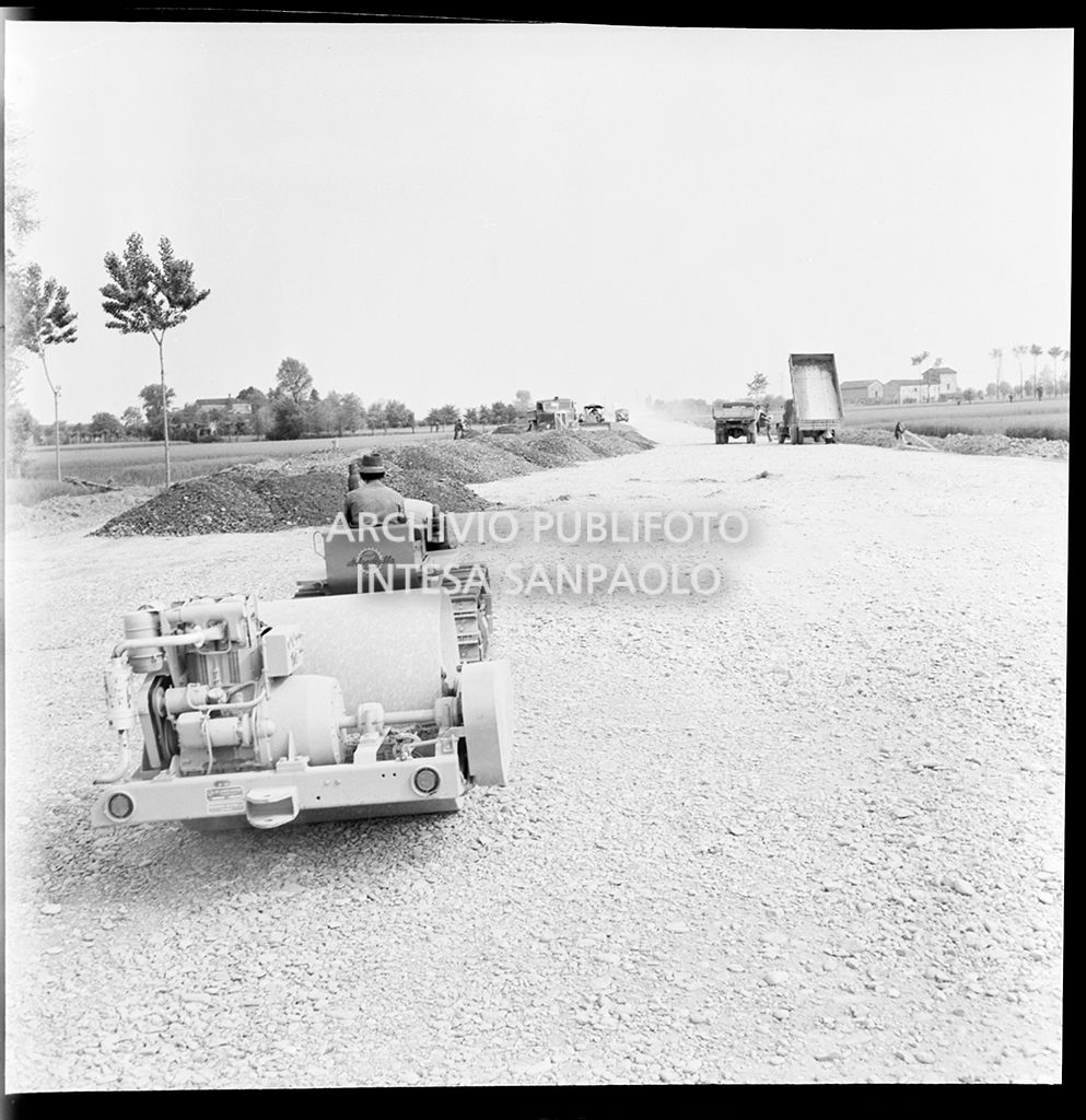Schiacciasassi e autocarri nel cantiere di costruzione dell'Autostrada del Sole nei pressi di Pontenure<br>383265
