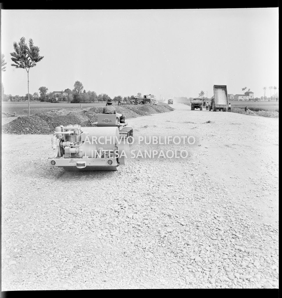 Schiacciasassi e autocarri nel cantiere di costruzione dell'Autostrada del Sole nei pressi di Pontenure<br>383266