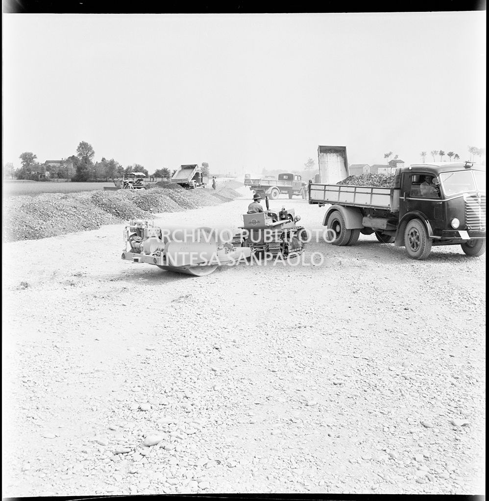 Schiacciasassi e autocarri nel cantiere di costruzione dell'Autostrada del Sole nei pressi di Pontenure<br>383268