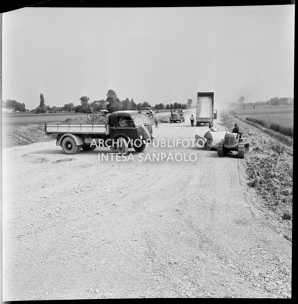 Schiacciasassi e autocarri nel cantiere di costruzione dell'Autostrada del Sole nei pressi di Pontenure<br>383269