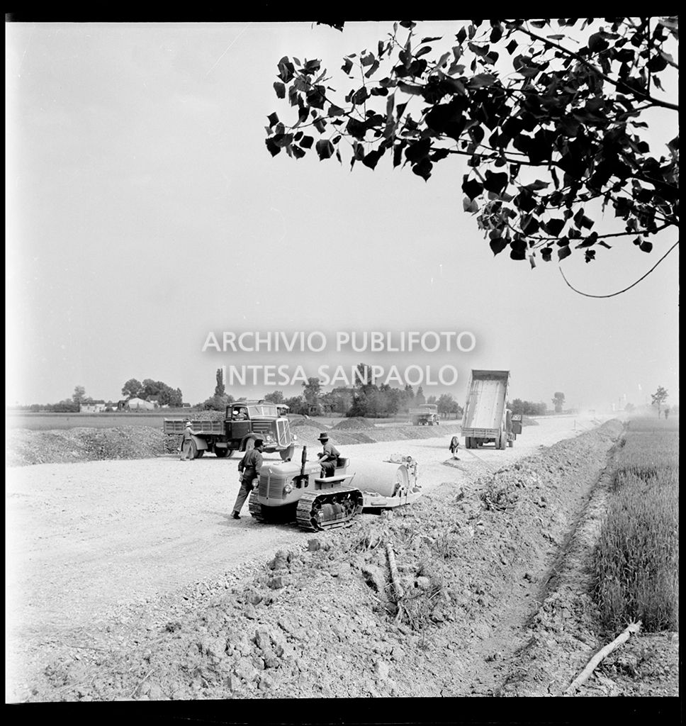 Schiacciasassi e autocarri nel cantiere di costruzione dell'Autostrada del Sole nei pressi di Pontenure<br>383270