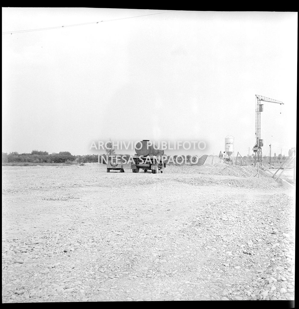 Autobotte e automobile nel cantiere di costruzione dell'Autostrada del Sole nei pressi di Pontenure<br>383271