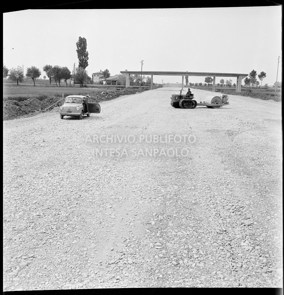Una Fiat 600 e uno schiacciasassi nel cantiere di costruzione dell'Autostrada del Sole nei pressi di Fontanellato, tratto Fidenza-Parma<br>383286