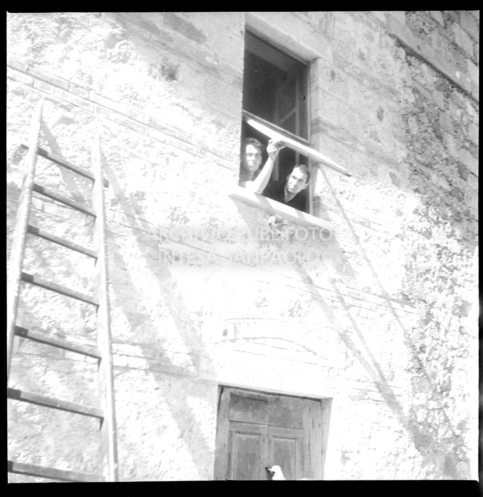 Due uomini affacciati a una finestra ad Abbadia San Salvatore nei giorni successivi alla tentata insurrezione e all'uccisione di due ufficiali di polizia, dopo l'attentato a Palmiro Togliatti<br>42121