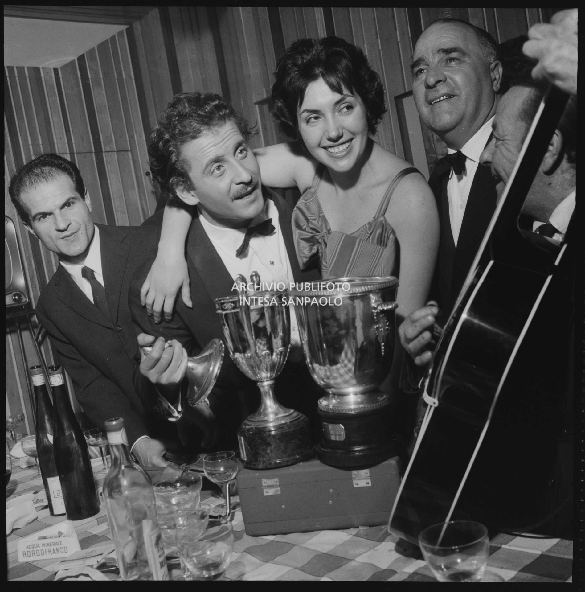 Domenico Modugno e la moglie Franca Gandolfi festeggiano con amici, al ristorante, il Festival di Sanremo appena vinto insieme a Johnny Dorelli con la canzone "Piove"