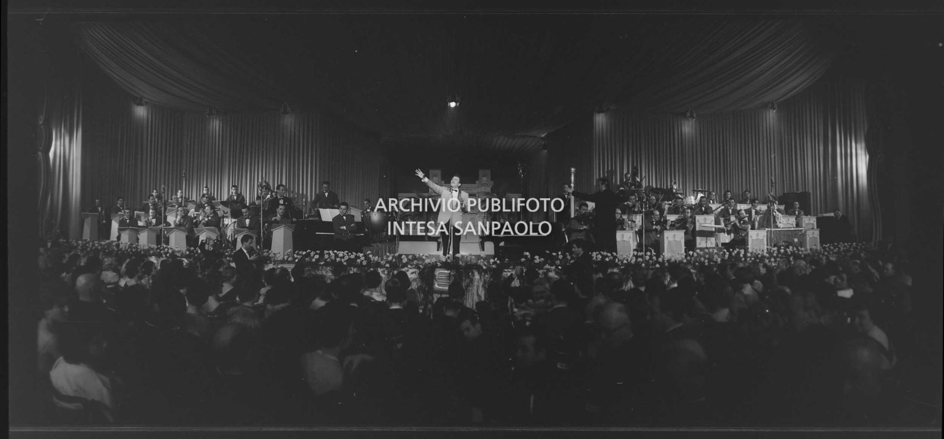 Domenico Modugno, si esibisce sul palco del Salone delle feste del Casinò al IX Festival di Sanremo, che vincerà, insieme a Johnny Dorelli, con la canzone "Piove"