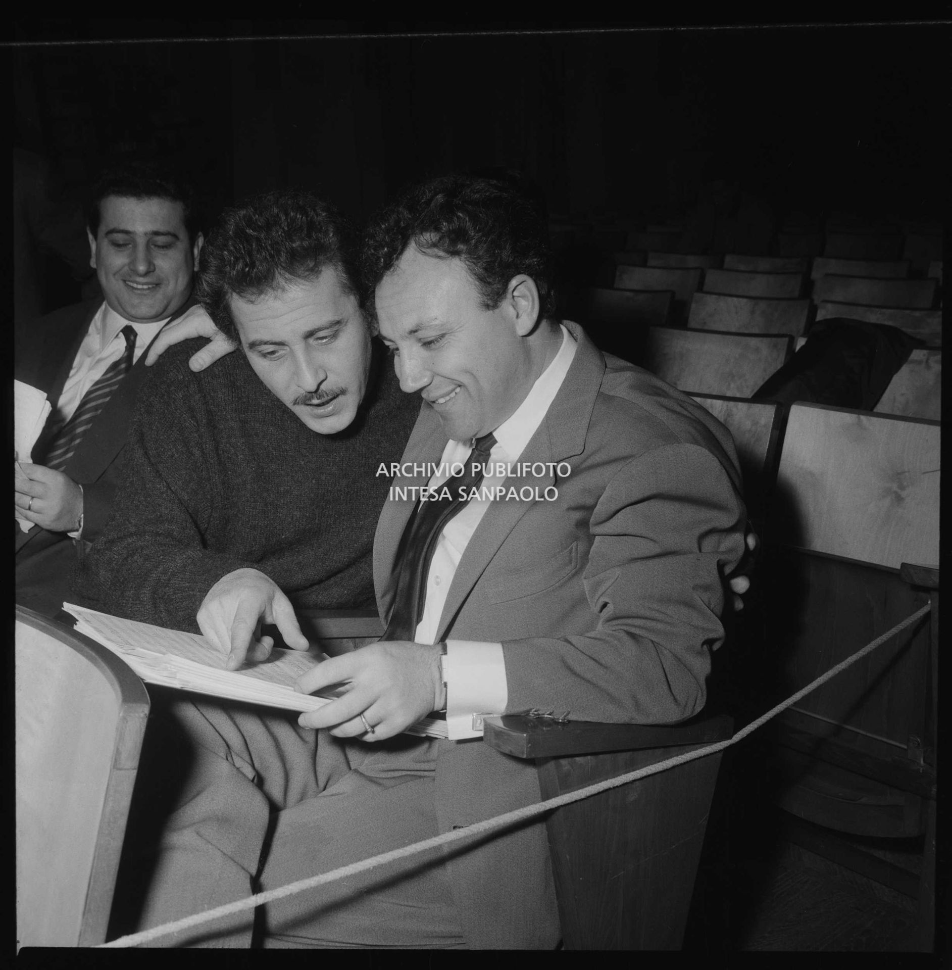 Da sinistra Domenico Modugno e Claudio Villa, seduti in platea durante le prove del Festival di Sanremo, leggono uno spartito musicale