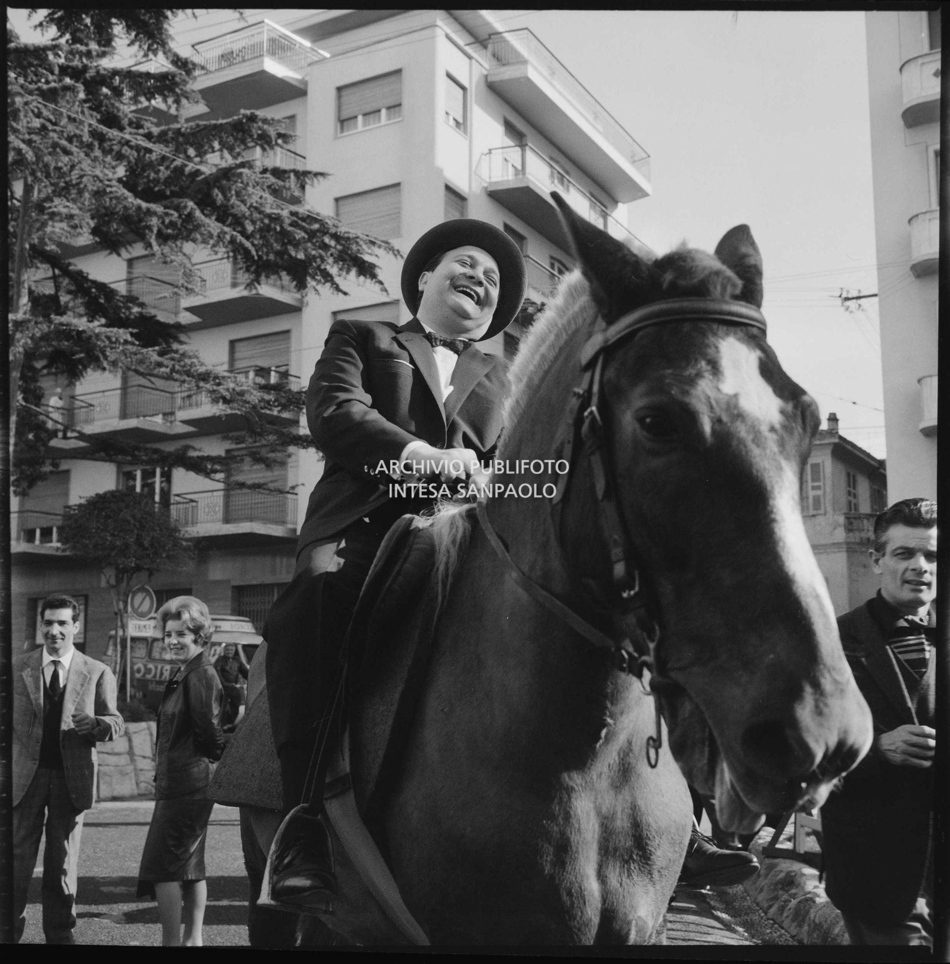 Aurelio Fierro ride in sella a un cavallo per le strade di Sanremo nei giorni del XII Festival dove presenta la canzone "Lui andava a cavallo"