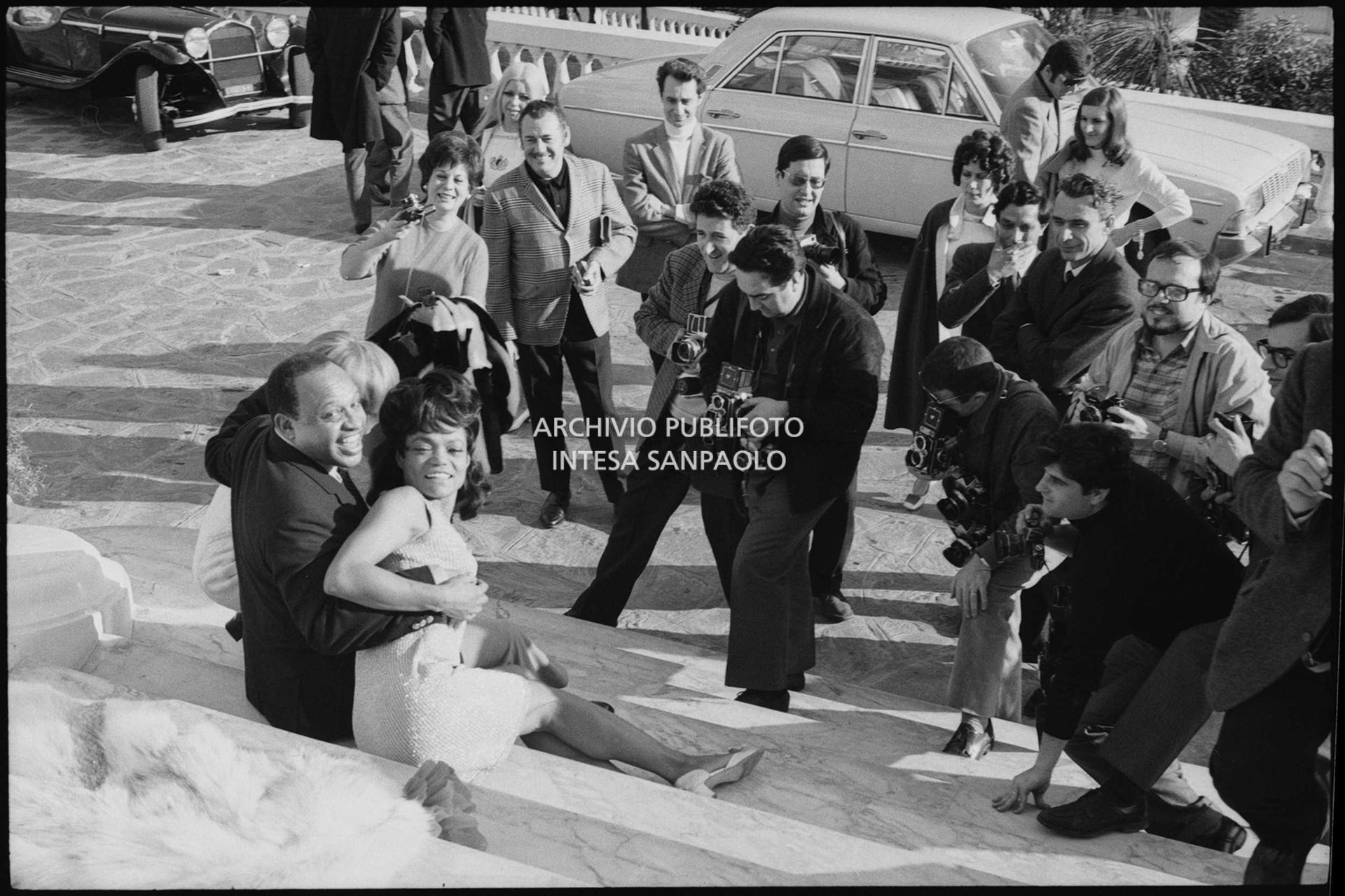 Lara Saint Paul, Lionel Hampton e Eartha Kitt attorniati da fotografi all'esterno del Casinò nei giorni del XVIII Festival della canzone italiana di Sanremo