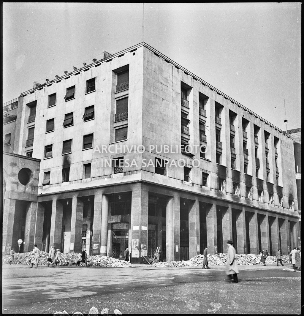 Palazzo della Reale Mutua Assicurazioni in piazza Diaz danneggiato dai bombardamenti; visibili cumuli di macerie per strada