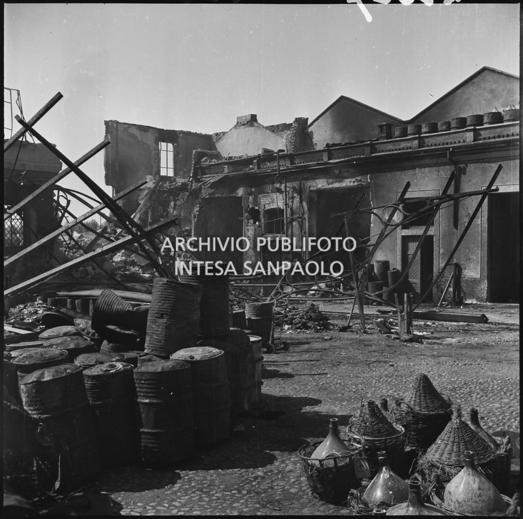 Panoramica del cortile interno dell'impresa Chiappetta danneggiata dai bombardamenti: a terra numerosi barili e macerie