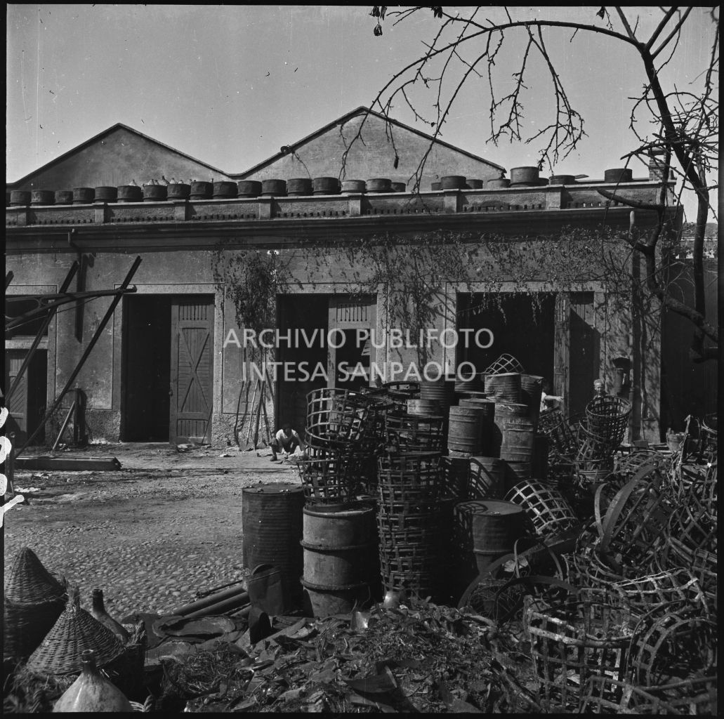 Panoramica del cortile interno dell'impresa Chiappetta danneggiata dai bombardamenti: a terra numerosi barili e macerie