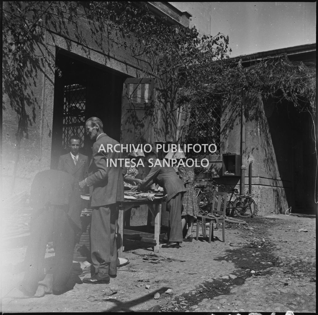 Un gruppo di persone recupera alcuni materiali nel cortile interno dell'impresa Chiappetta danneggiata dai bombardamenti