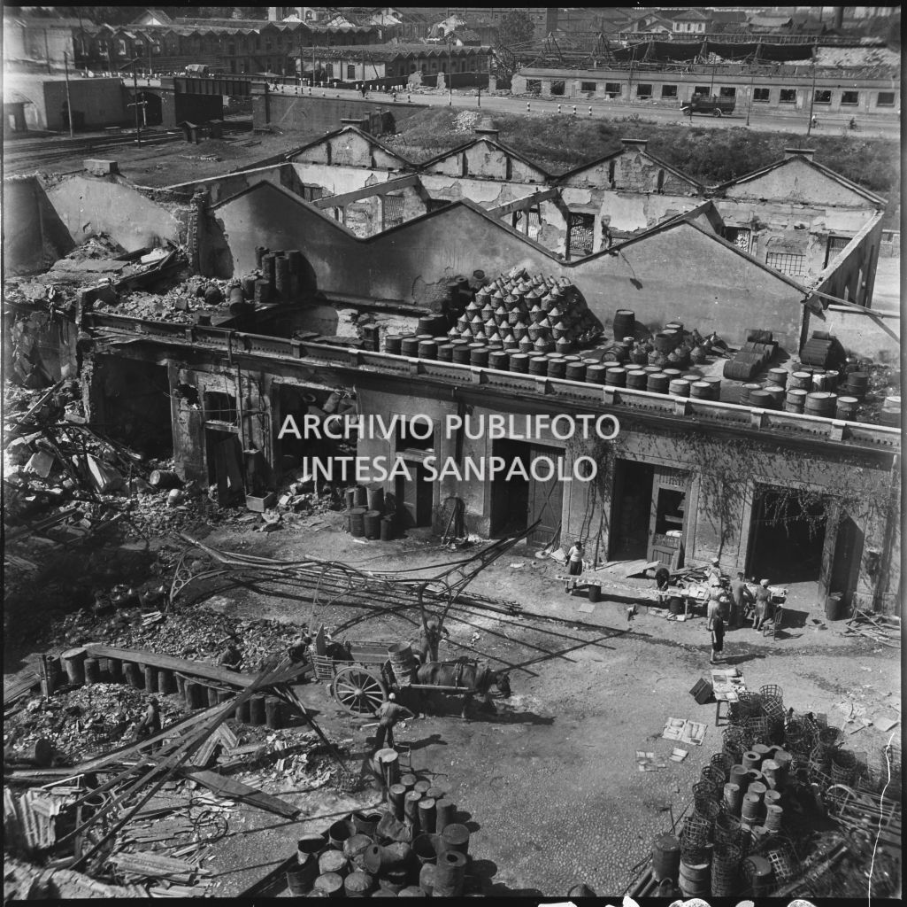 Ripresa dall'alto di un gruppo di persone che recupera alcuni materiali nel cortile interno dell'impresa Chiappetta danneggiata dai bombardamenti