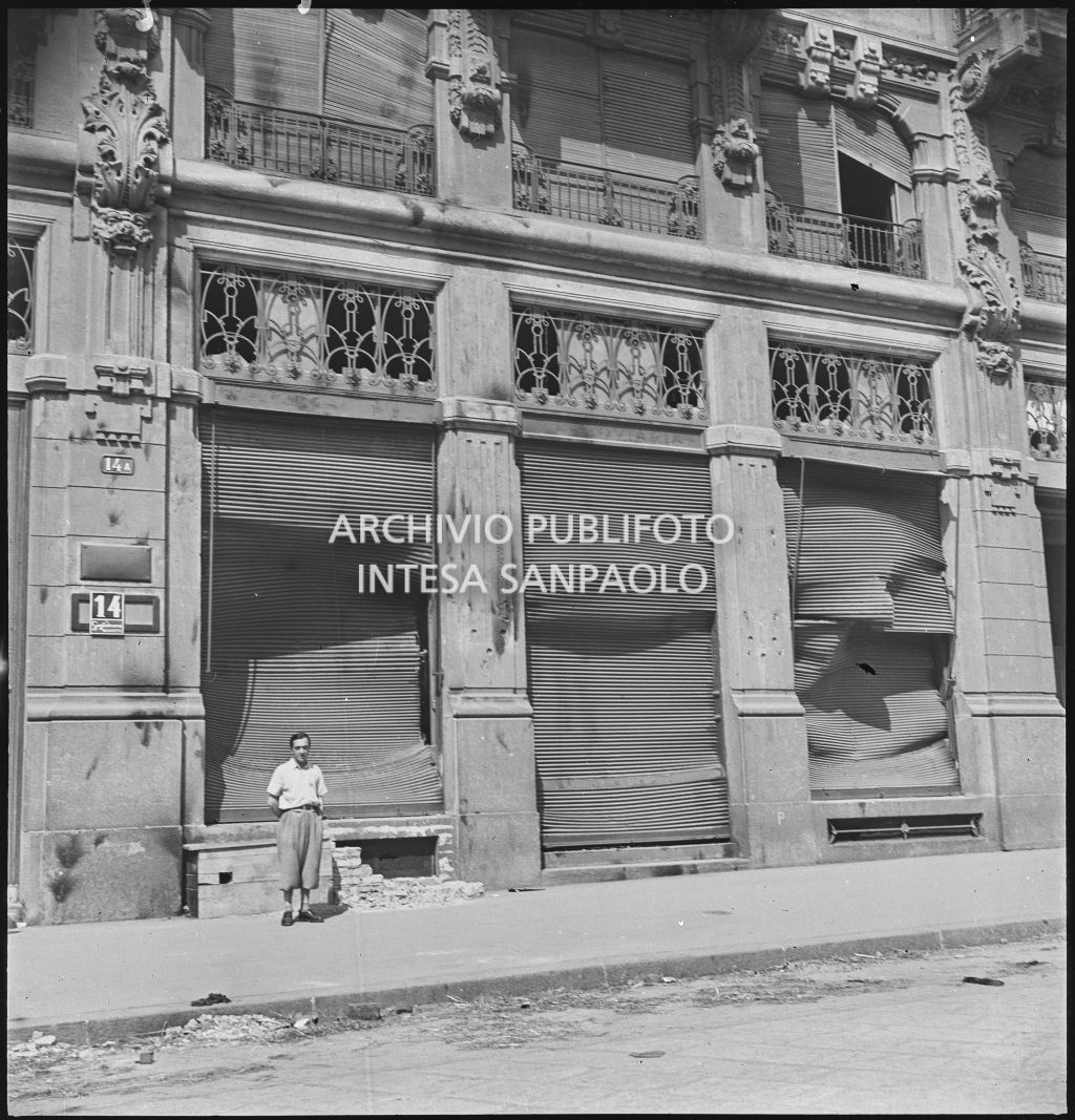 Un uomo in posa davanti alle saracinesche divelte di viale Monte Grappa 14 dove aveva sede la Società Anonima Casalegno colpita dai bombardamenti