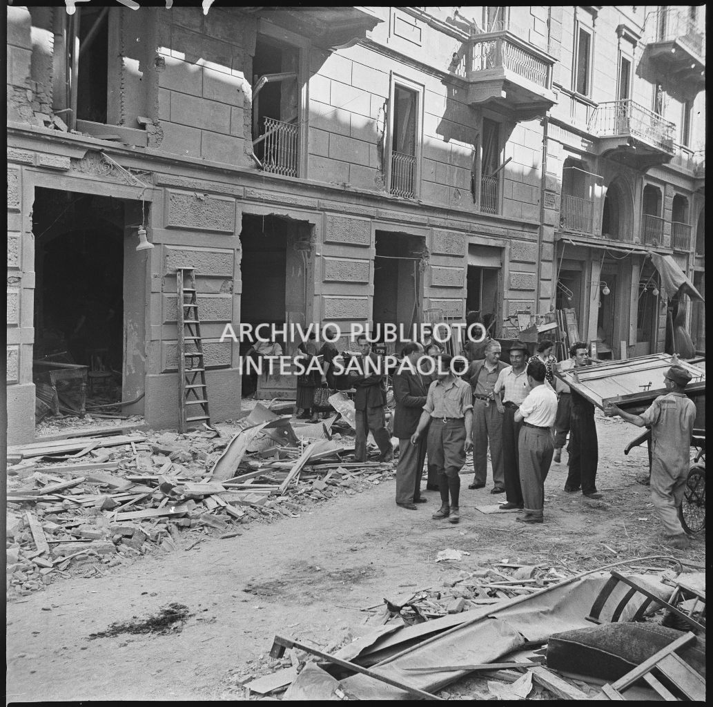 Un edificio gravemente danneggiato dai bombardamenti, in via Settala a Milano, davanti al quale ci sono numerose persone tra cui anche un militare