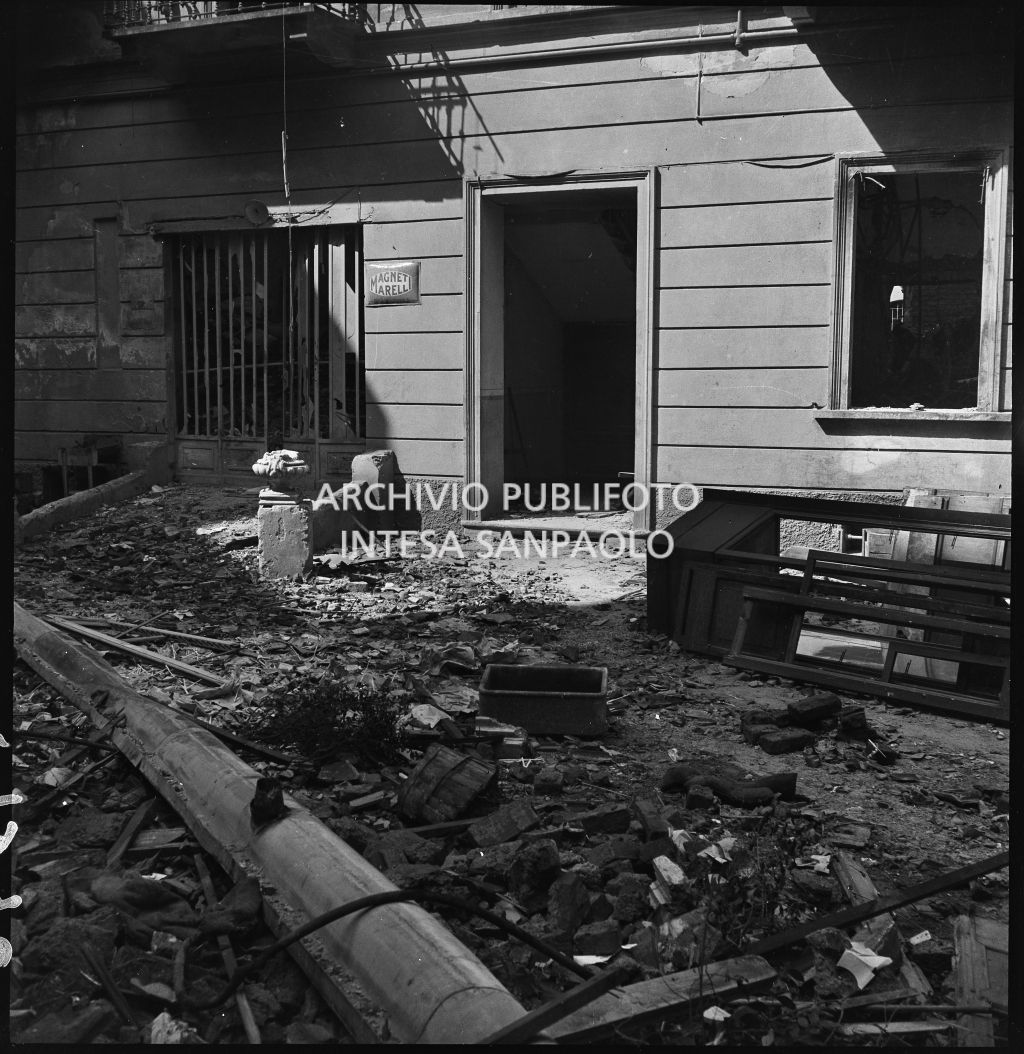 Cortile della sede della Società Anonima L'Autoaccessorio, in piazza Duca d'Aosta, a Milano, distrutta dai bombardamenti. A lato dell'ingresso la targa con la scritta "Magneti Marelli"