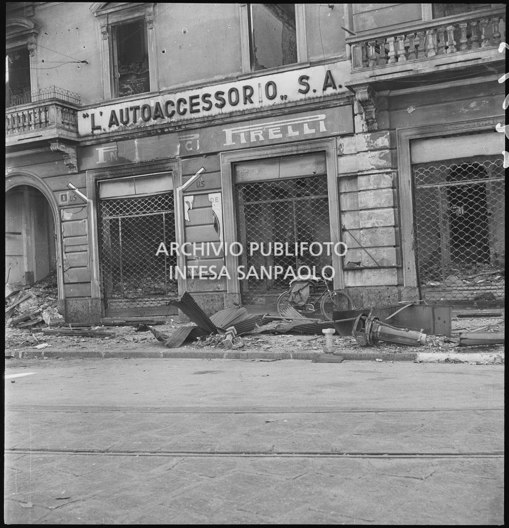 Vetrine della Società Anonima L'Autoaccessorio, in piazza Duca d'Aosta, a Milano, sventrata dai bombardamenti. Sul muro i segnali "U.S." indicano l'uscita di sicurezza