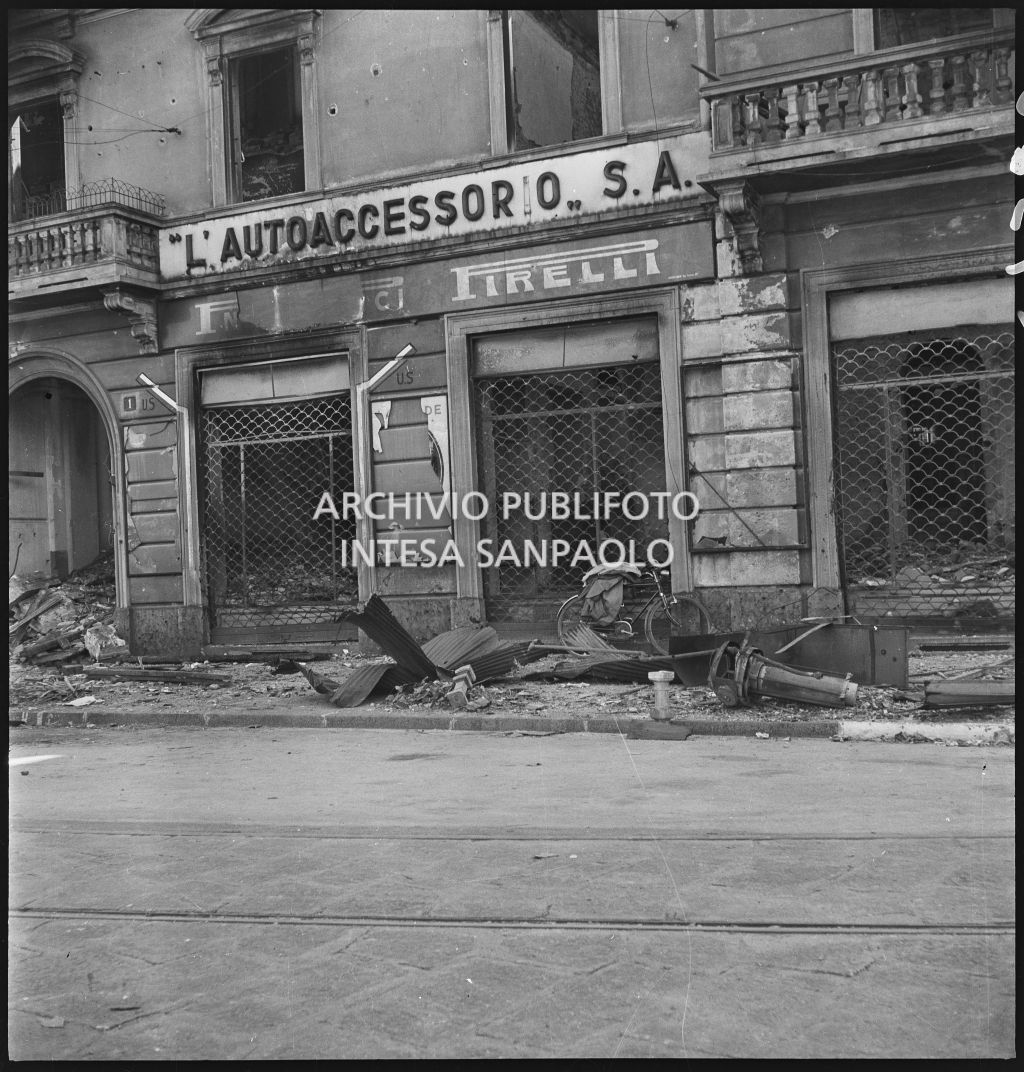 Vetrine della Società Anonima L'Autoaccessorio, in piazza Duca d'Aosta, a Milano, sventrata dai bombardamenti. Sul muro i segnali "U.S." indicano l'uscita di sicurezza