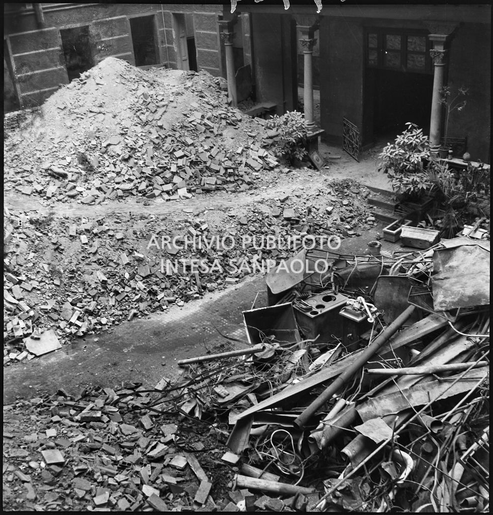 Macerie e detriti dei bombardamenti in un cortile: è visibile la carcassa di una cucina economica