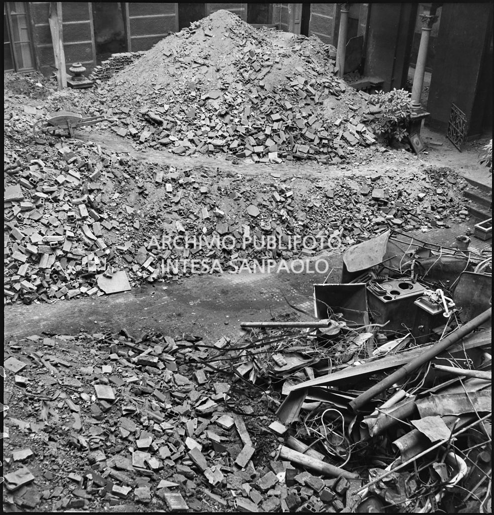 Macerie e detriti dei bombardamenti in un cortile: è visibile la carcassa di una cucina economica