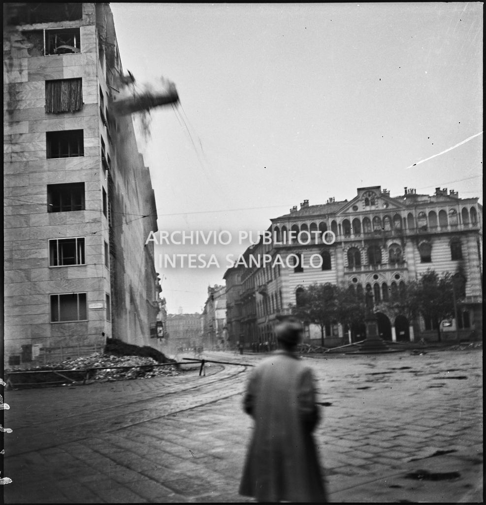 Un uomo osserva il Palazzo Montecatini, in via della Moscova a Milano, gravemente danneggiato dai bombardamenti, durante la demolizione delle strutture pericolanti; sulla destra il Palazzo Maciachini