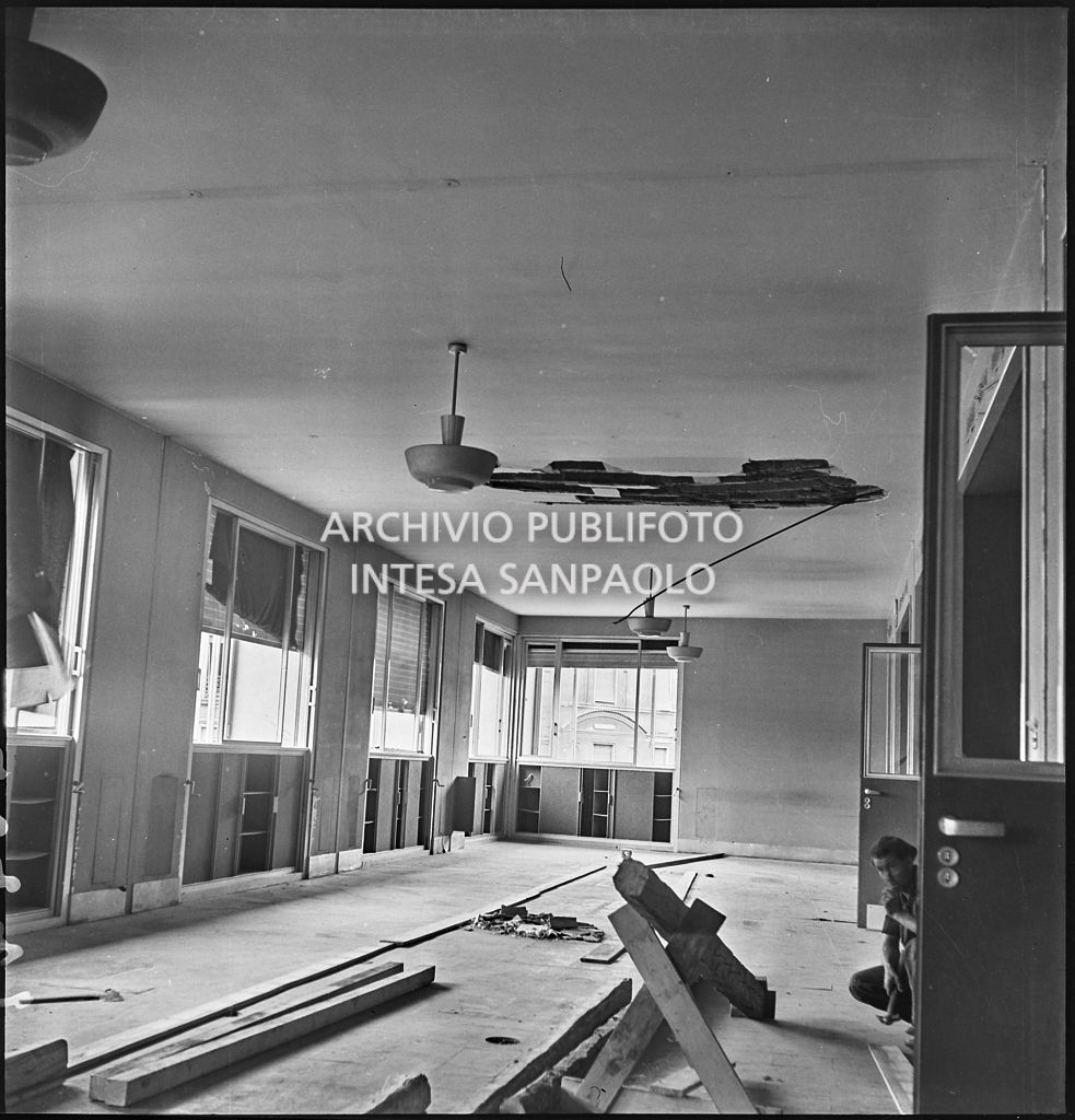 Interno di Palazzo Montecatini, in via della Moscova a Milano, danneggiato dai bombardamenti; sulla destra, accosciato, un uomo con martello