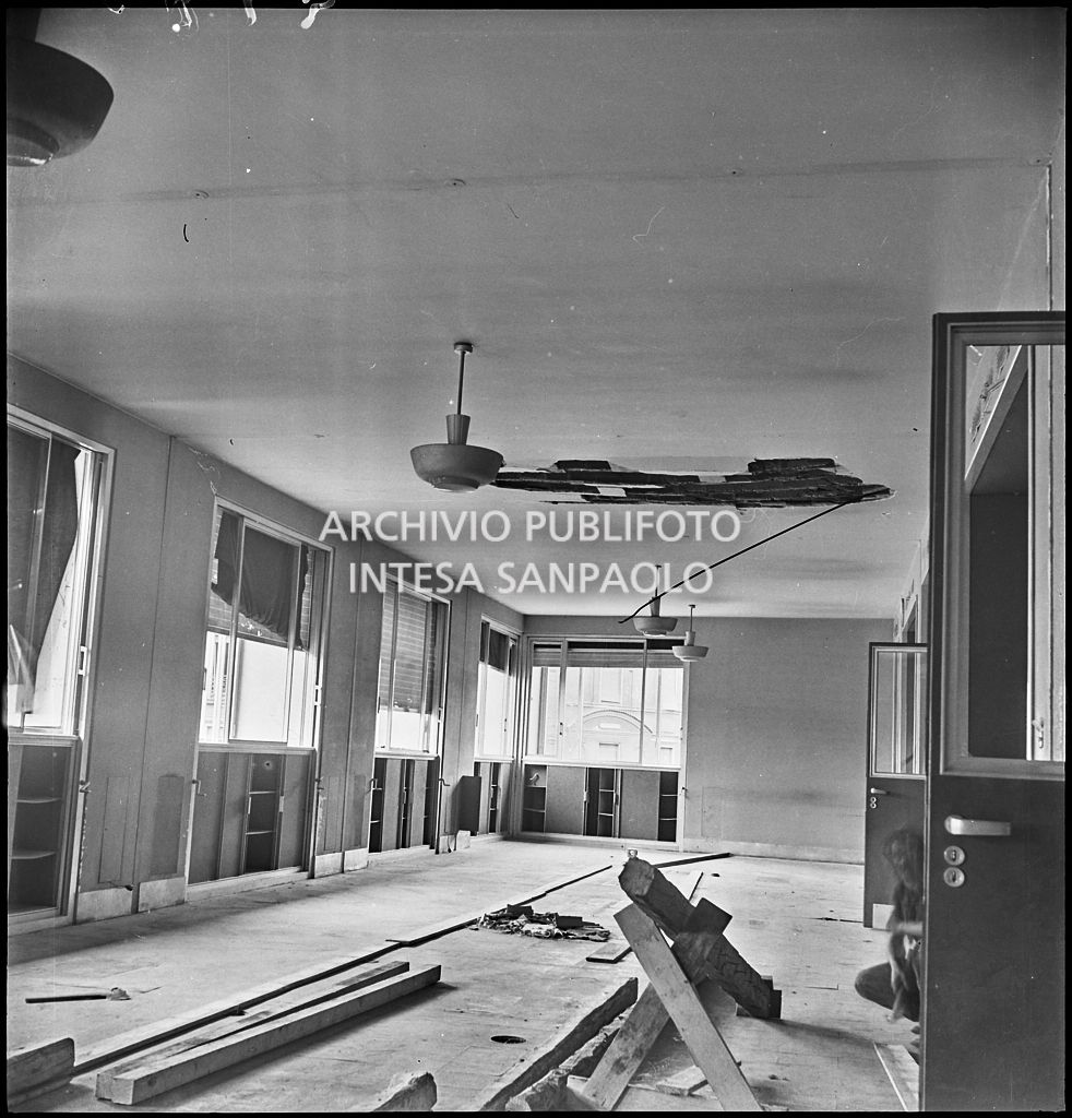 Interno di Palazzo Montecatini, in via della Moscova a Milano, danneggiato dai bombardamenti; sulla destra, accosciato, un uomo con martello