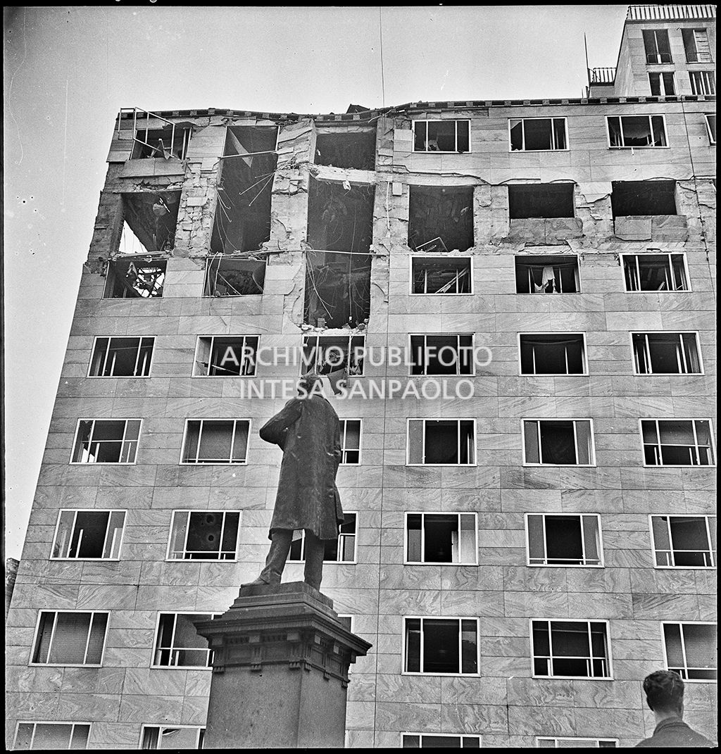 Palazzo Montecatini, in via della Moscova a Milano, gravemente danneggiato dai bombardamenti; i piani superiori sono sventrati e un pilastro è pericolante; in primo piano il monumento ad Agostino Bertani