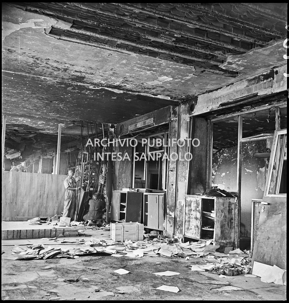 Interno di un piano di Palazzo Montecatini, in via della Moscova a Milano, dopo i bombardamenti che hanno gravemente danneggiato l'edificio; sullo sfondo a destra due uomini in tuta da lavoro
