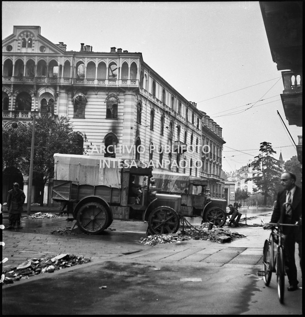 Due autocarri militari in sosta in via Principe Amedeo; sullo sfondo Palazzo Maciachini danneggiato dai bombardamenti