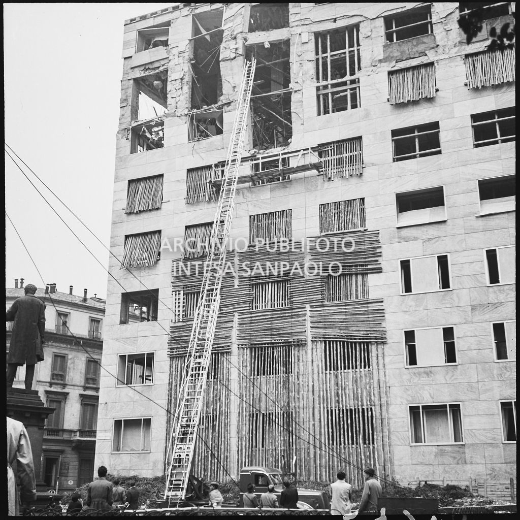 Operazioni di messa in sicurezza, anche con l'aiuto di un'autoscala, di Palazzo Montecatini, in via della Moscova a Milano, gravemente danneggiato dai bombardamenti; i piani superiori sono sventrati e un pilastro è pericolante. In basso a sinistra si intravede il monumento a Agostino Bertani