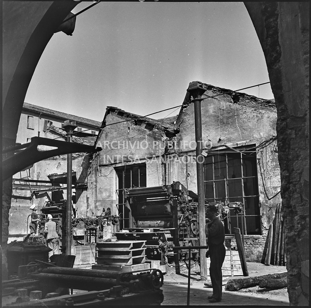 Lavoratori della Società Anonima Parini Vanoni & C., in via Bezzecca a Milano, controllano i danni dei bombardamenti ai macchinari dello stabilimento dello stabilimento tipo-cromo-litografico