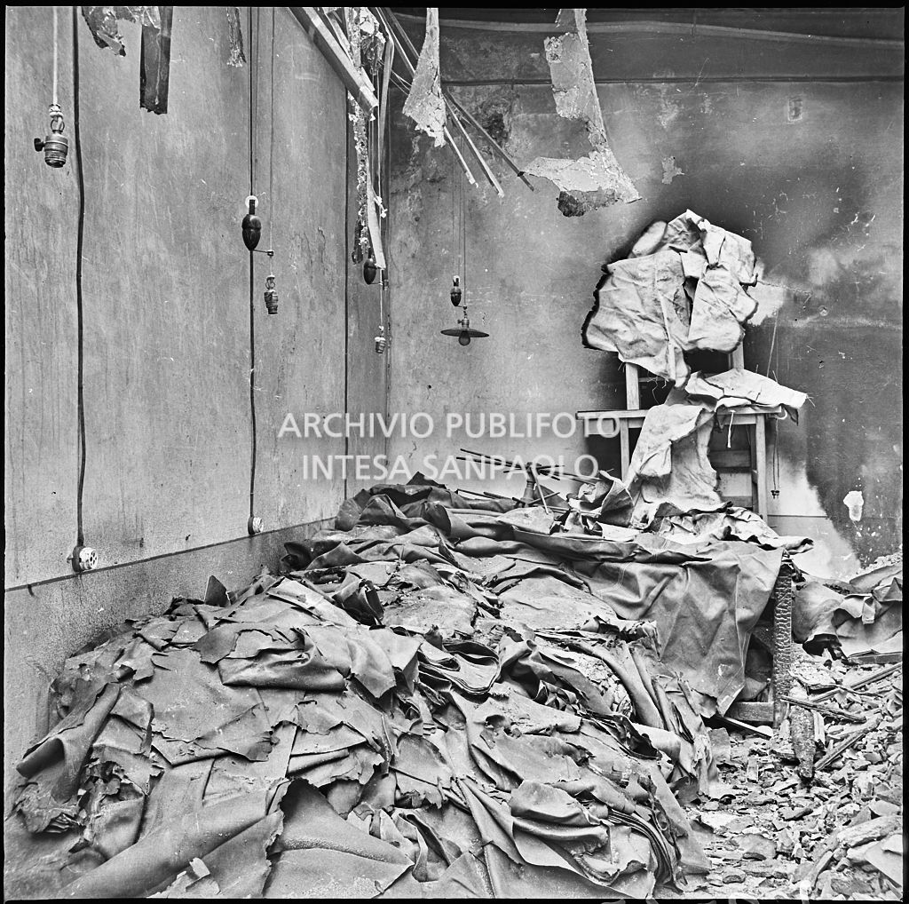Macerie e materiale, probabilmente, di produzione all'interno della ditta R. Romanelli, a Milano, che produceva copertoni e tendoni impermeabili, gravemente danneggiata dai bombardamenti