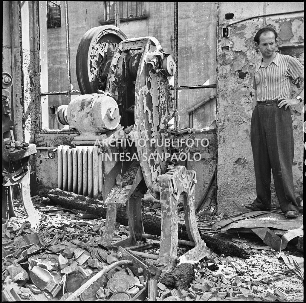Un uomo osserva  i danni causati dai bombardamenti presso lo Stabilimento italiano lavori in carta affini (SILICA), in corso di Porta Nuova a Milano; in primo piano un macchinario