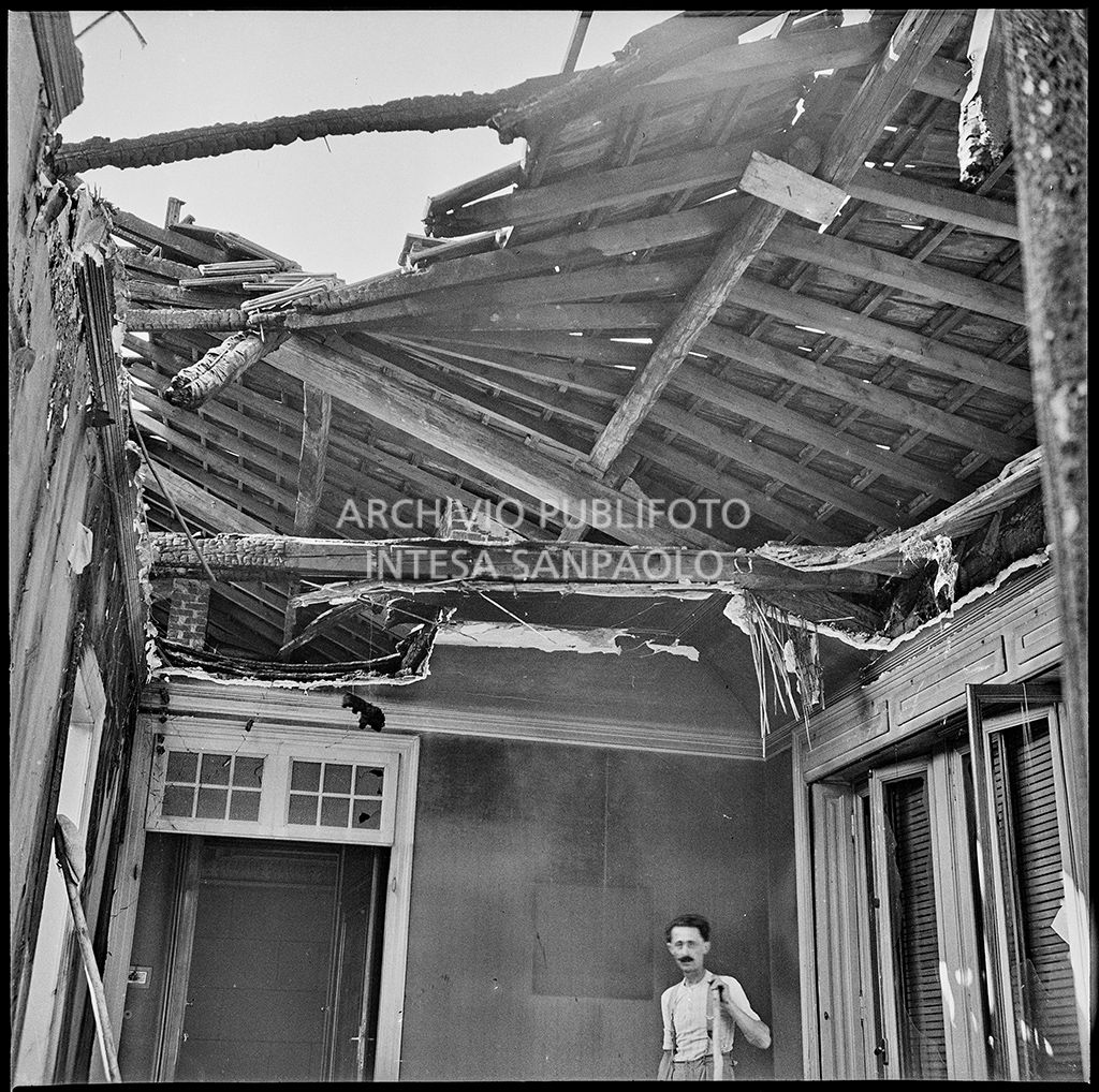 Interno di un appartamento, a Milano, gravemente danneggiato dai bombardamenti che hanno distrutto il tetto; a destra un uomo in maglietta
